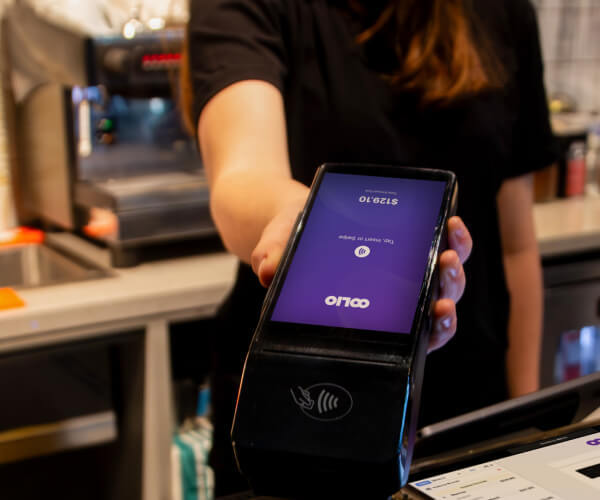 Staff member taking payment with integrated Oolio payment terminal