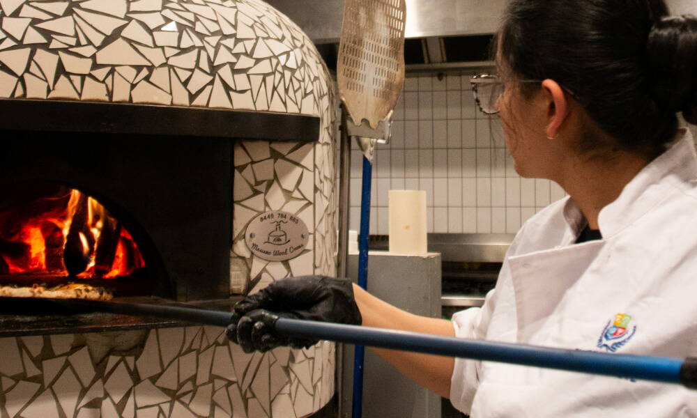 Chef pulling a pizza out of the pizza oven