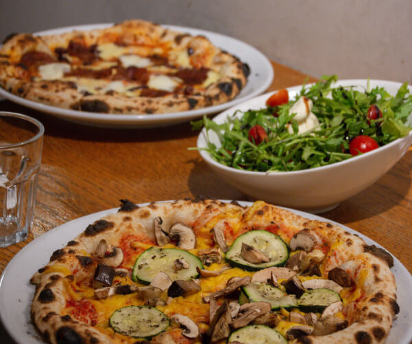 Pizzas and salad served as a Pizzeria