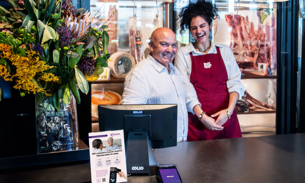 Happy team members behind the counter with Oolio Giving flyer