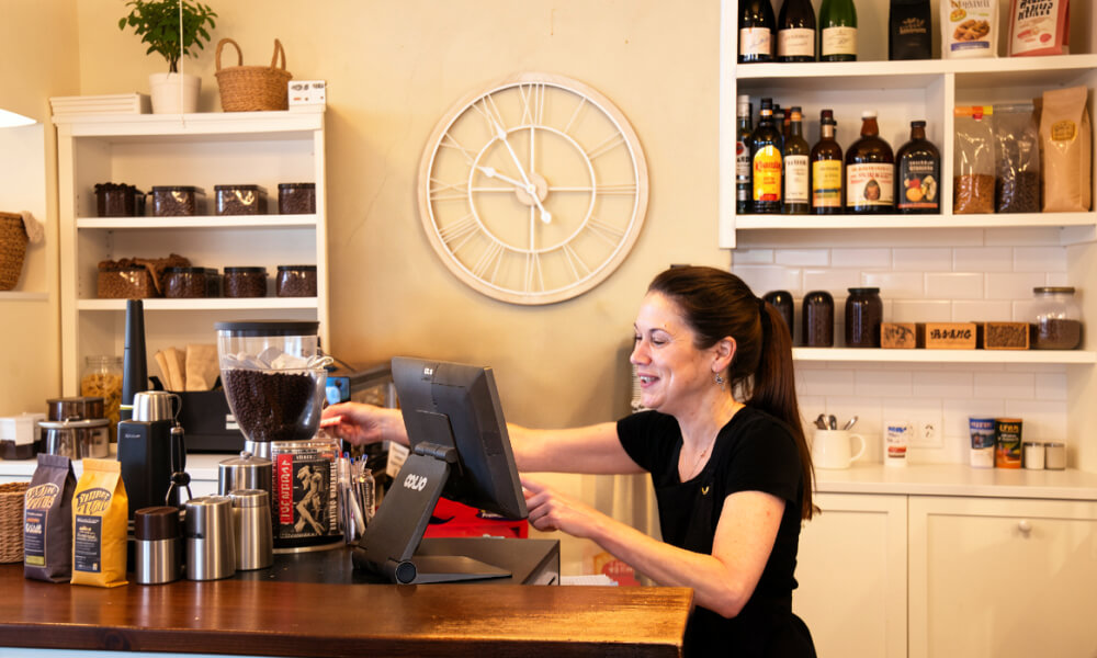 Happy staff at a cafe using a POS at counter