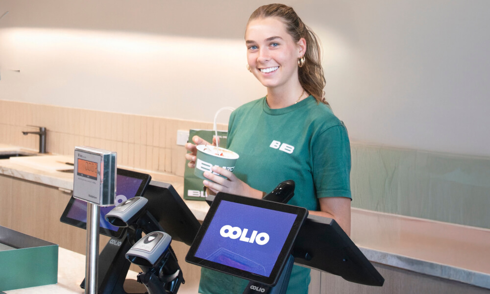 Staff member behind the counter with Oolio Customer Display showing