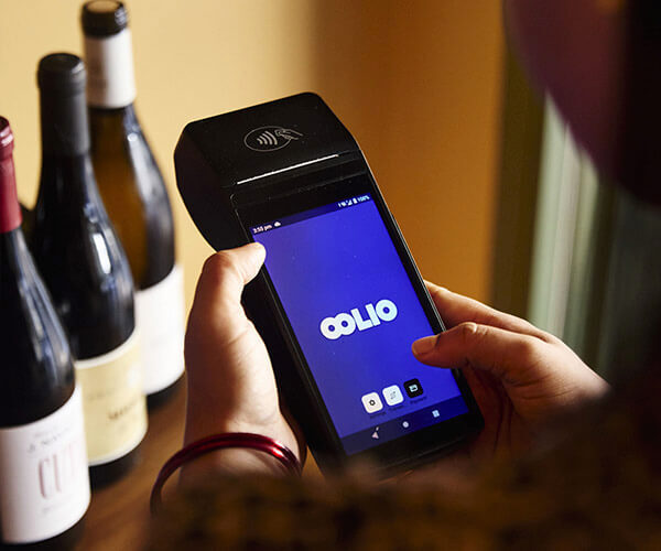 Oolio payment terminal in front of wine bottles
